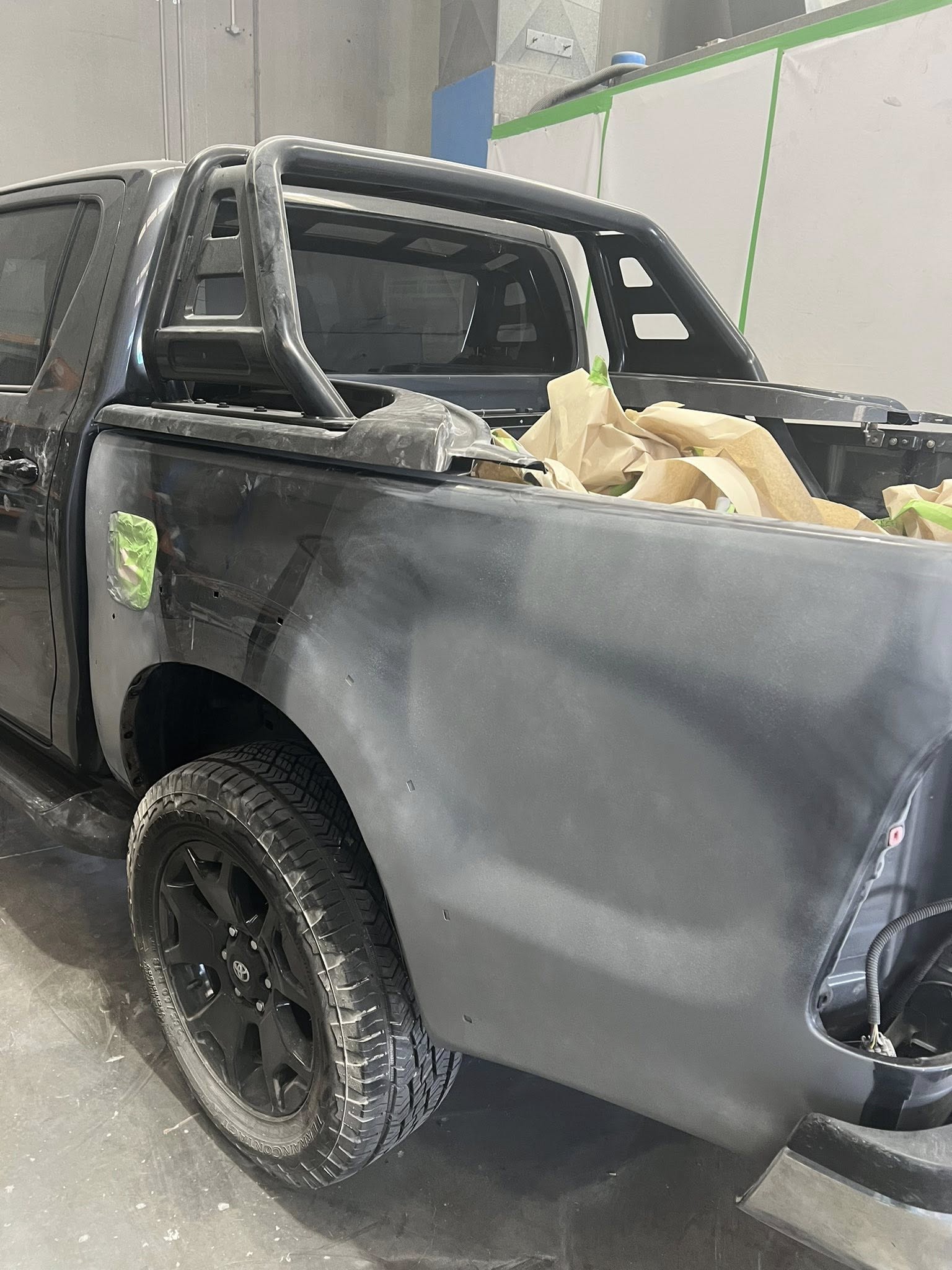 Black Toyota HiLux ute with tub panels sanded back to bare metal for repair